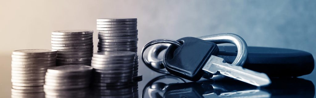 Stacks of coins next to a set of car keys.